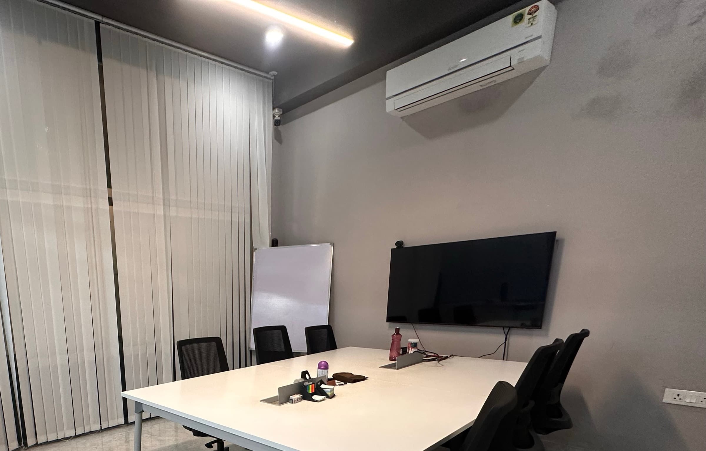 Meeting room with a white meeting table, wall-mounted display and whiteboard
